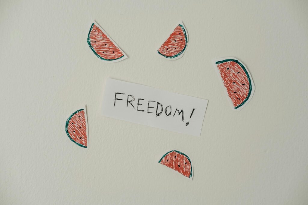 Artistic watermelon illustration surrounding the word 'Freedom' on paper.