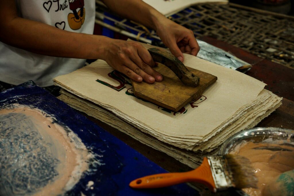 Close-up of an artisan using a wooden stamp for paper printing in a traditional workshop.
